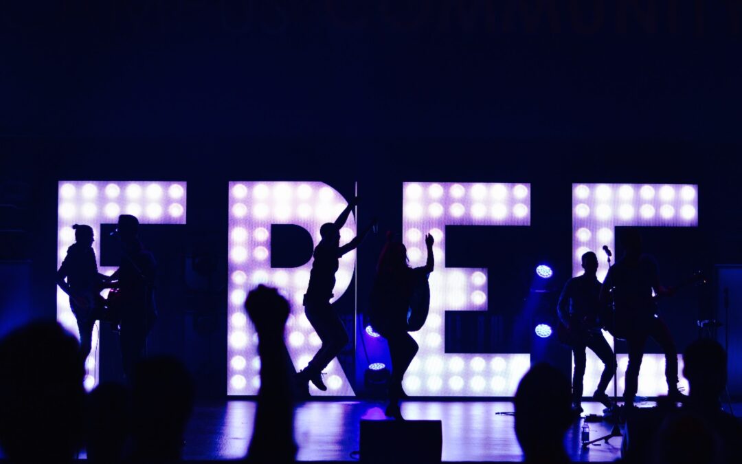 silhouette of people in front of light up letters that spell "FREE"